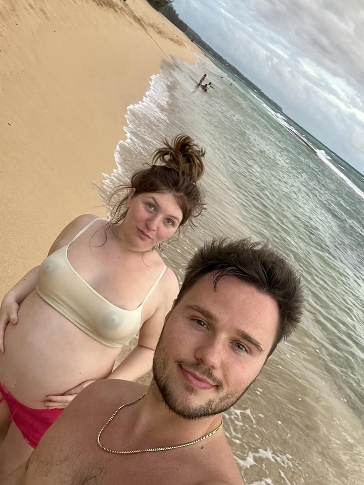 Pregnant woman shows her belly on beach