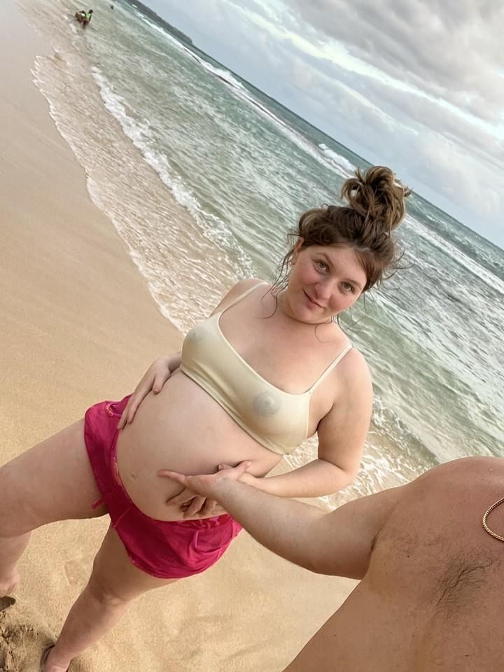 Pregnant woman shows her belly on beach