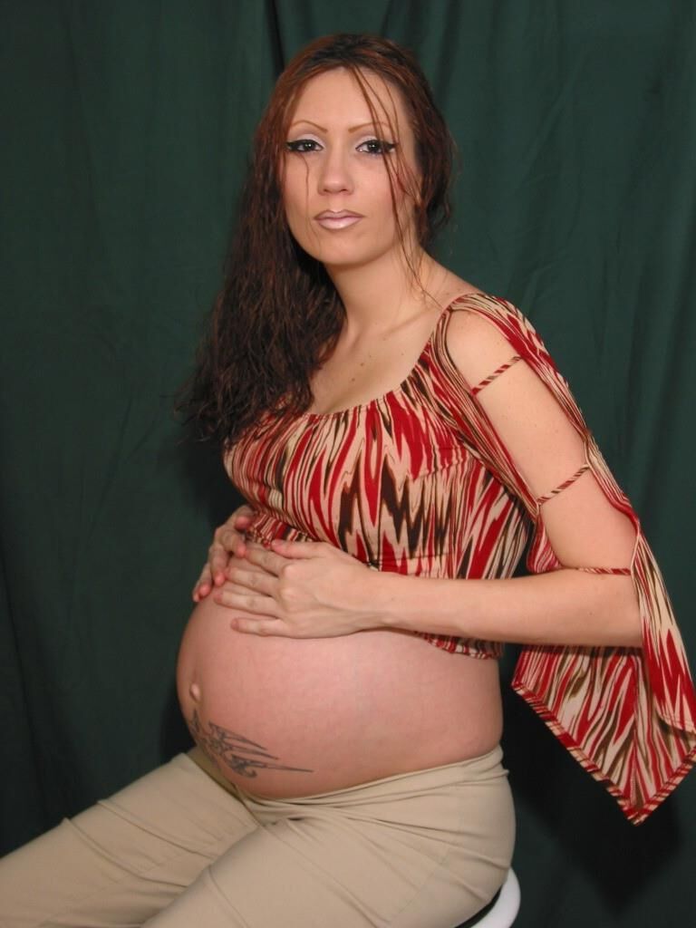 A sexy pregnant woman poses naked on a stool