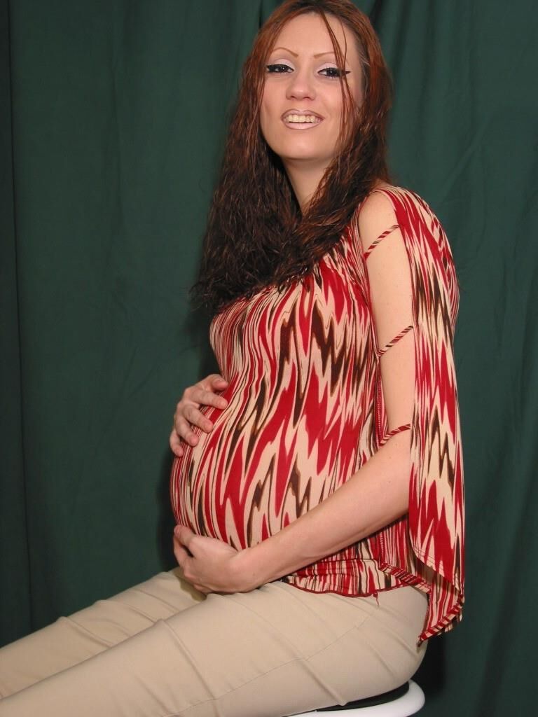 A sexy pregnant woman poses naked on a stool